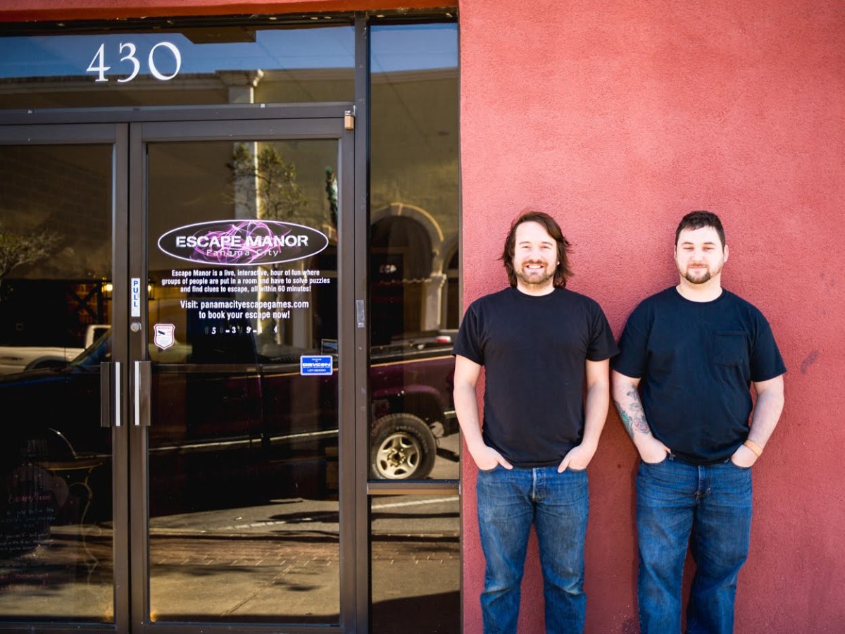 two men standing in front of red wall