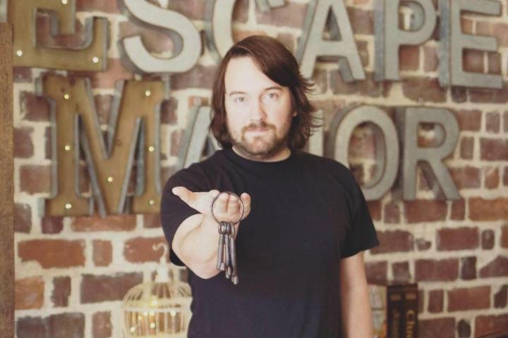 Man holding keys in front of Escape Manor sign